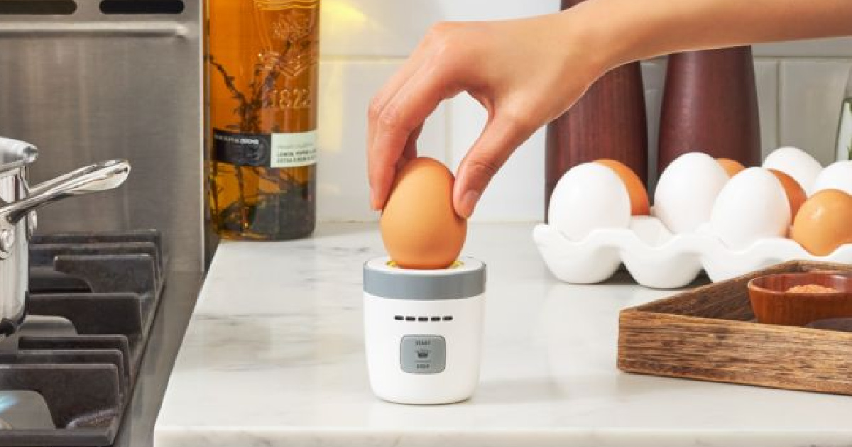 hand holding an egg over a timer in a kitchen