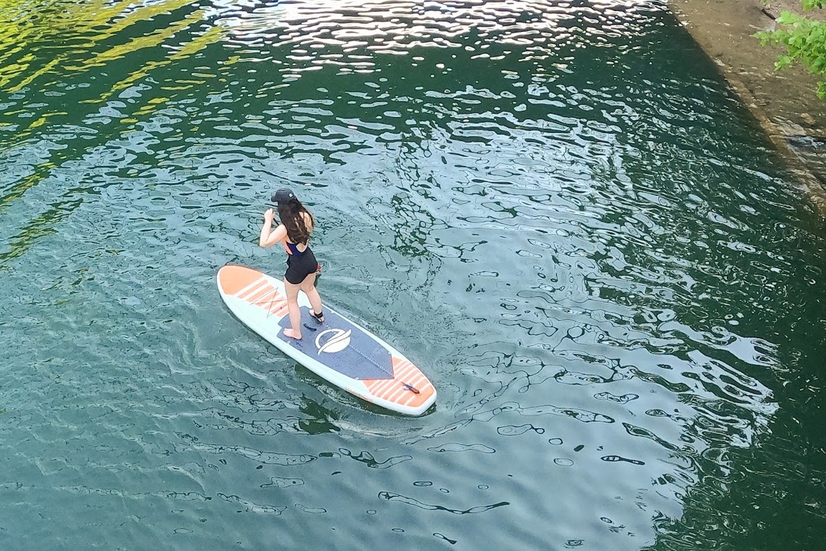 Woman on inflatable paddle board in lake
