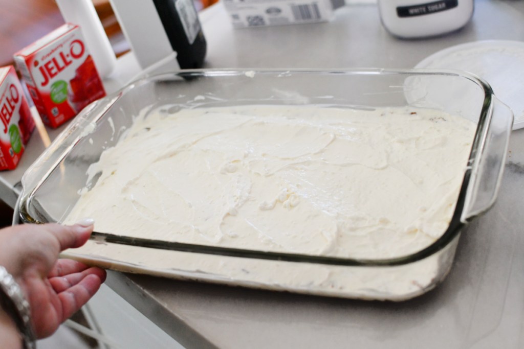 spreading cream cheese layer of strawberry dessert