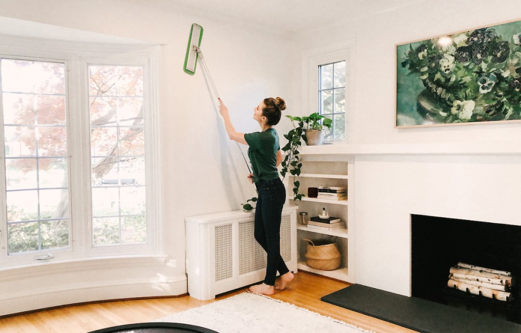 woman using turbo mop on wall in living room