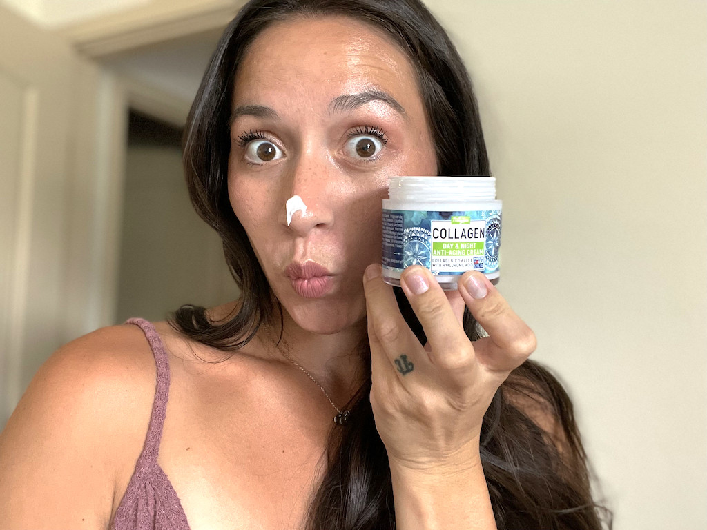 woman holding Collagen cream with it on her nose 