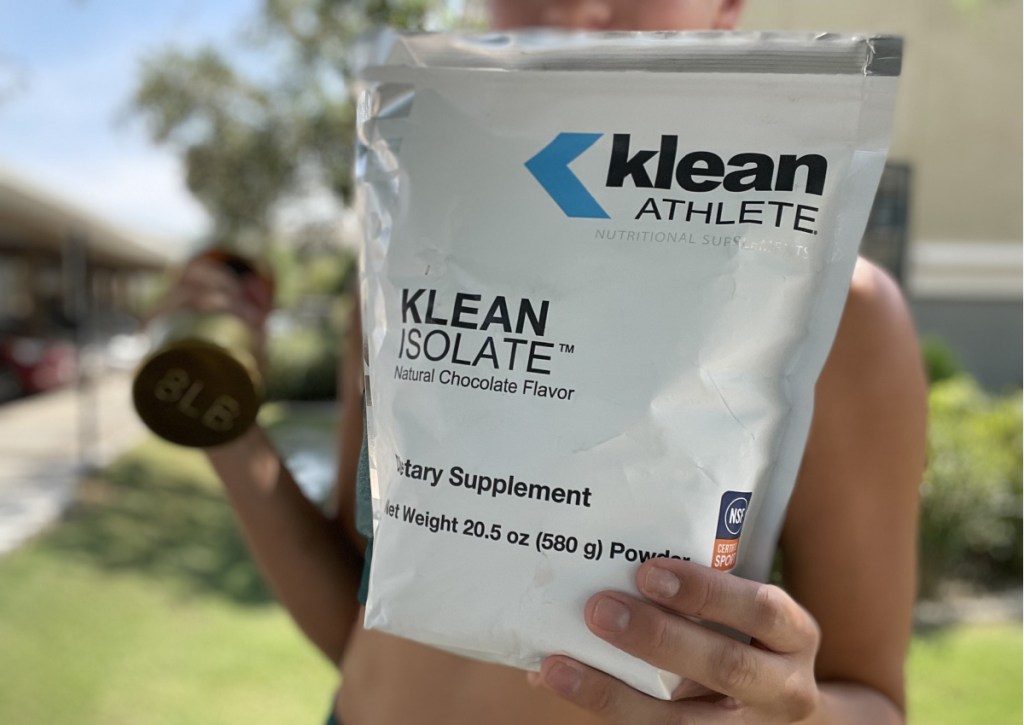 woman holding klean athlete powder outside