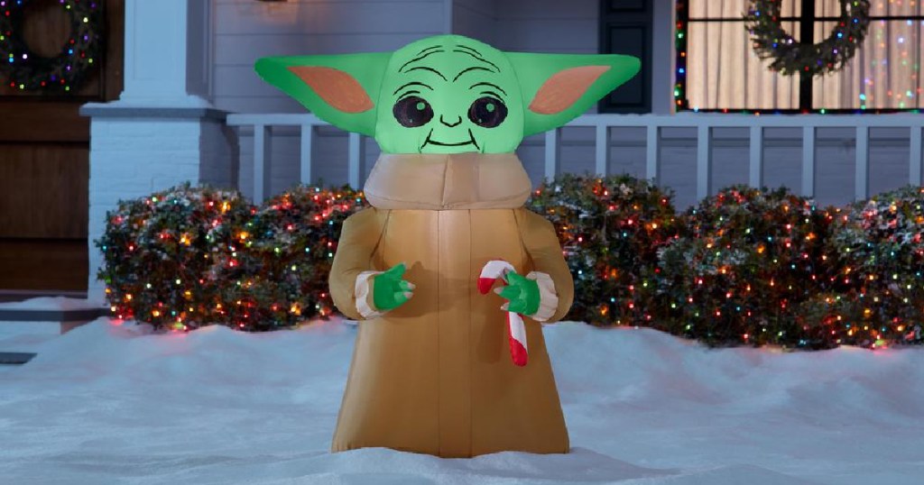 baby yoda christmas lawn inflatable in front of a porch and shrubs with christmas lights