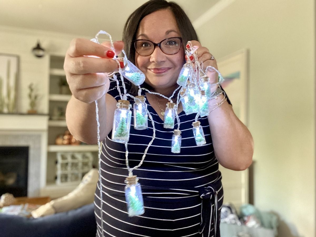 امرأة تحمل سلسلة أضواء زجاجة شجرة عيد الميلاد