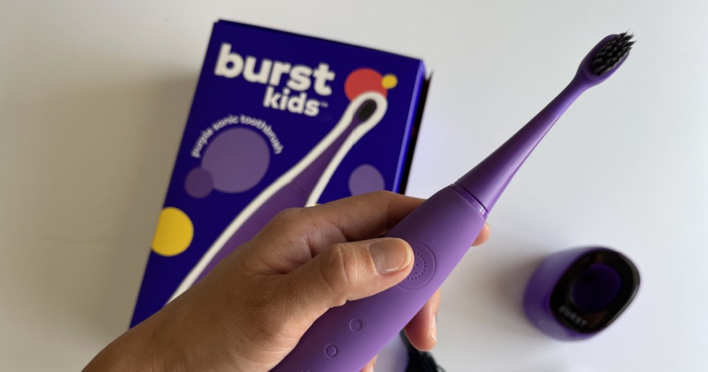 Woman holding purple colored kids electric toothbrush