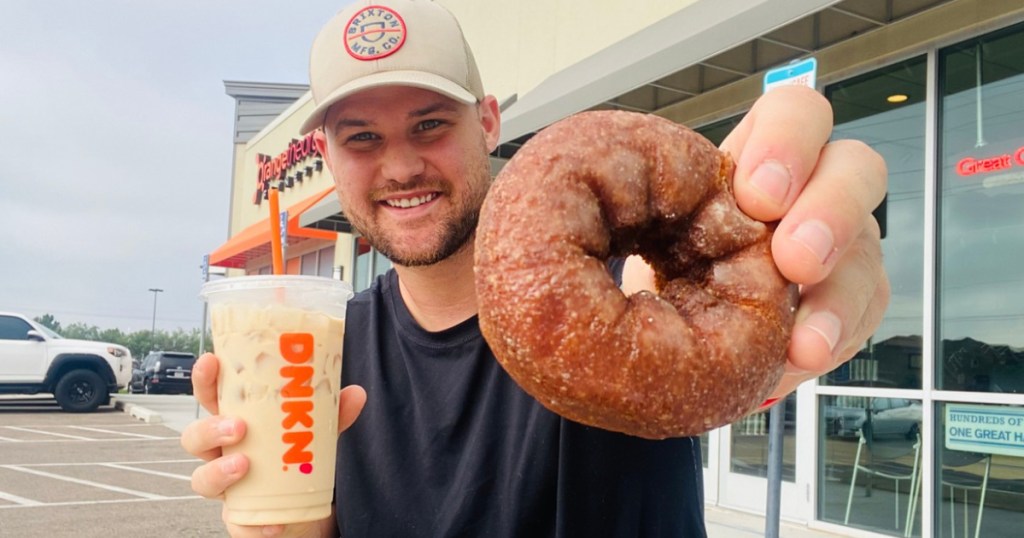 man holding a donut and coffee