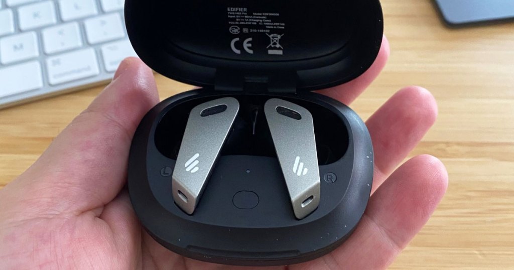 hand holding pair of earbuds in black charging case