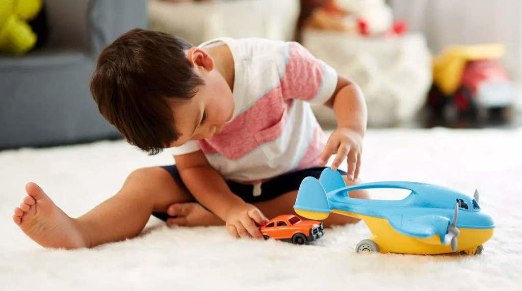 boy playing with a toy plane and car