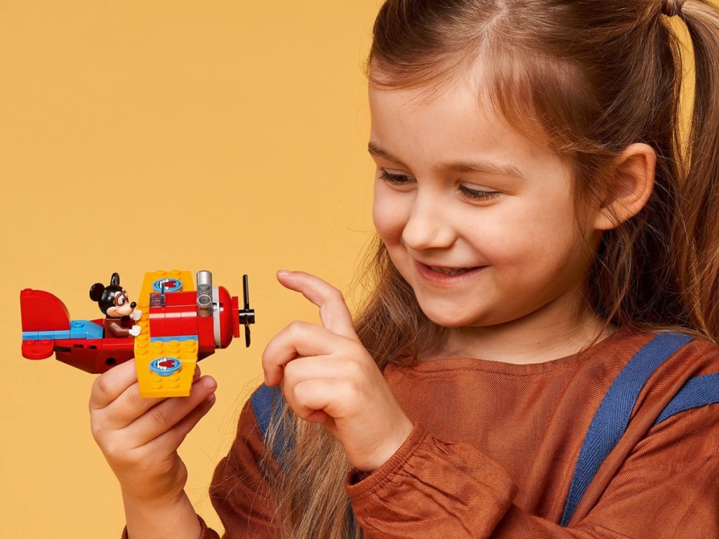 little girl holding mickey mouse plane lego set 