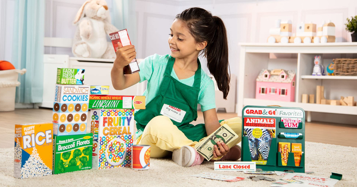 girl sitting on the floor with melissa and doug play store food