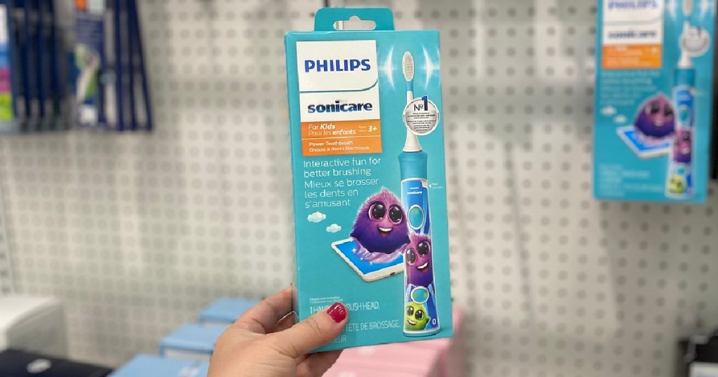 woman's hand holding kids toothbrush in store
