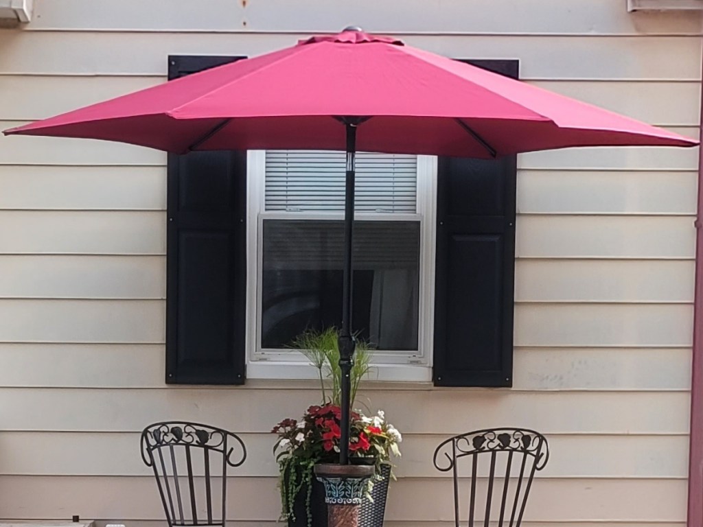 red umbrella with patio chairs in front of house