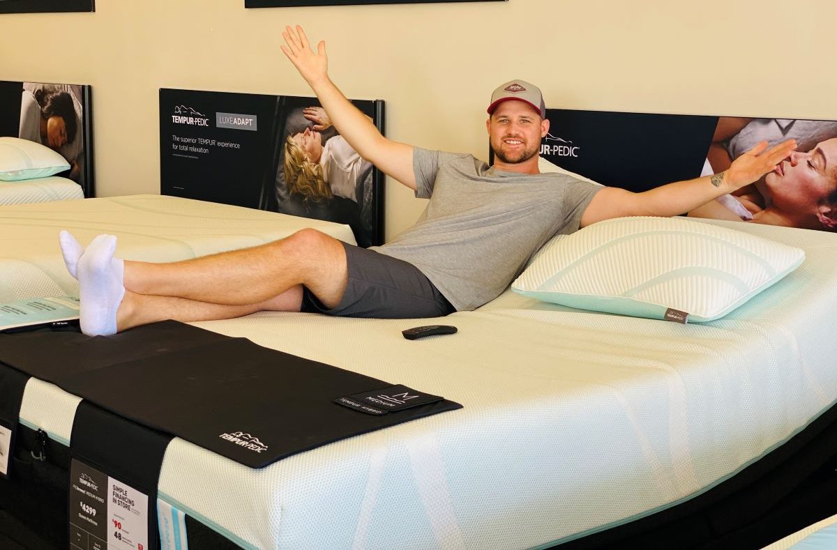 man sitting on a mattress in a store
