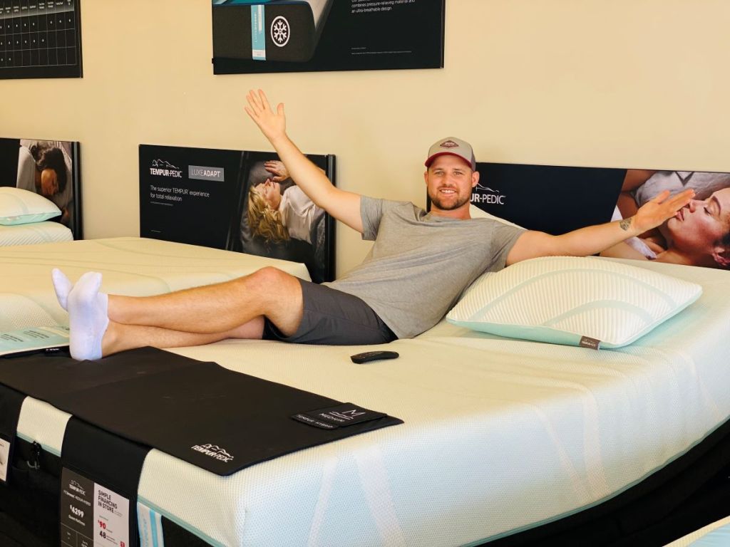 man sitting on a mattress in a store