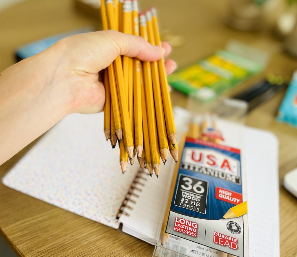 hand holding a bunch of yellow number two pencils
