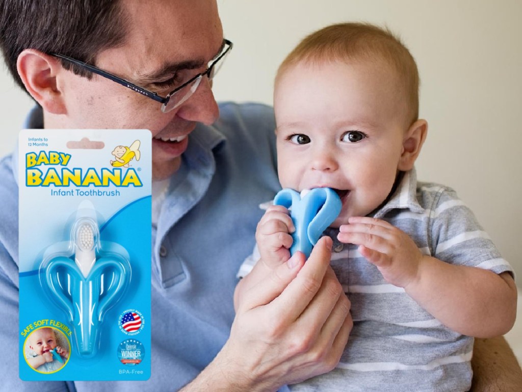 dad and baby sitting down smiling while baby has toy in mouth