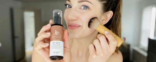 woman with brush on face holding beauty by earth self tanner for face