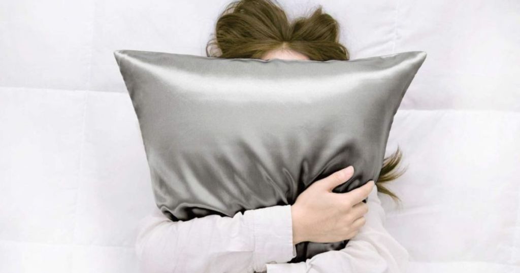 woman holding a gray satin pillow