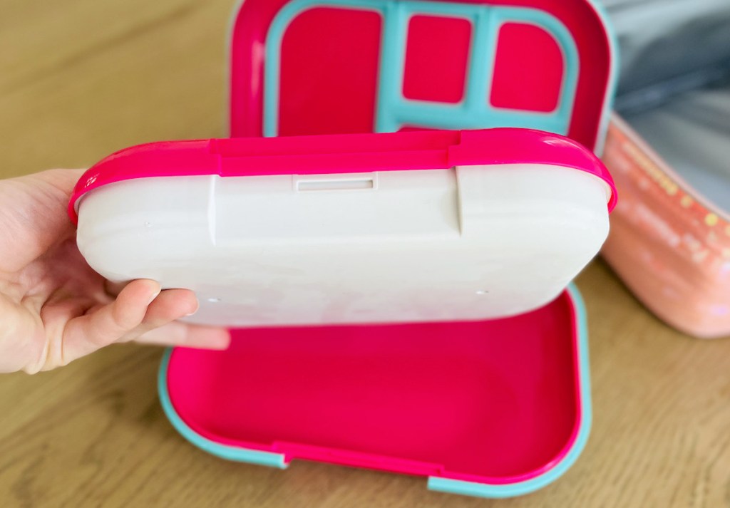 hand holding a bento lunchbox over wood table