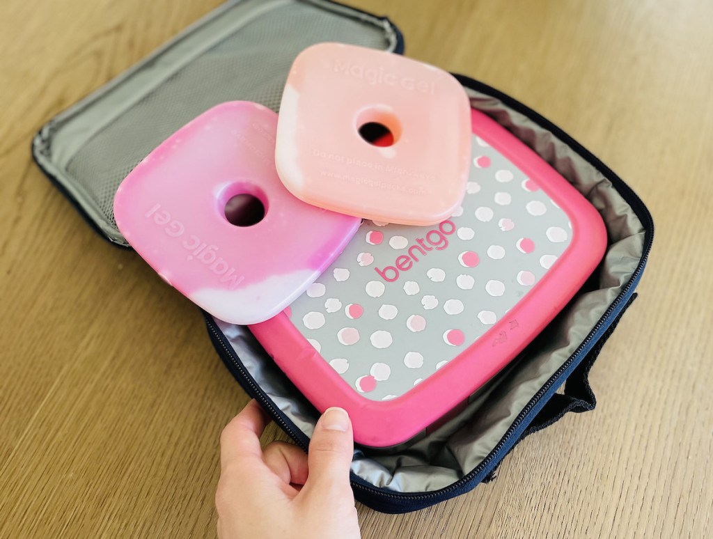 hand holding corner of lunch box with bentgo box and ice packs inside