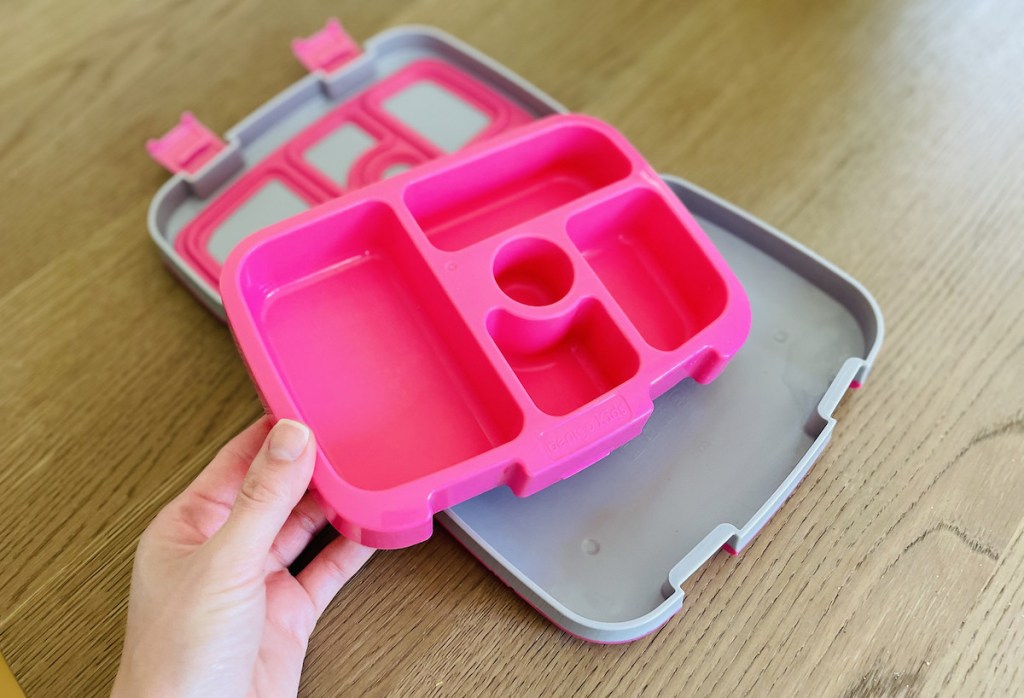 hand holding pink tray from bento box 