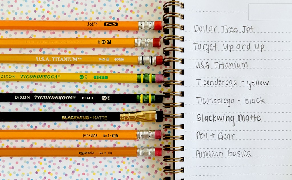 various types of pencils on notebook with brand names on paper