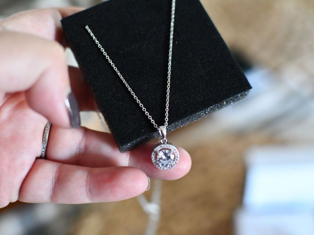hand holding silver diamond pendant