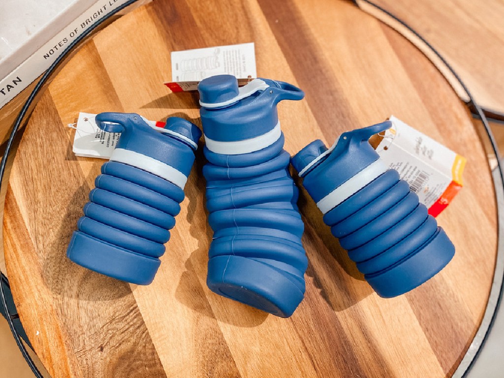three blue water bottles on wood cutting board
