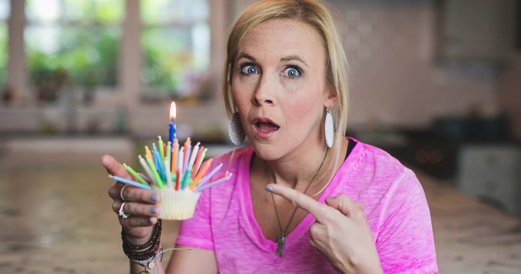 woman holding cupcake with tons of candles on top