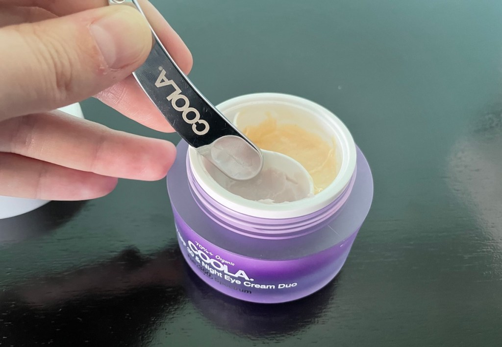 hand dipping coola stick into eye cream container