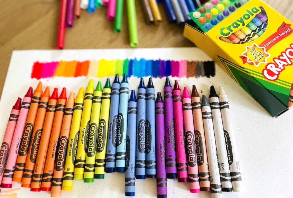rainbow row of crayola crayons on white paper