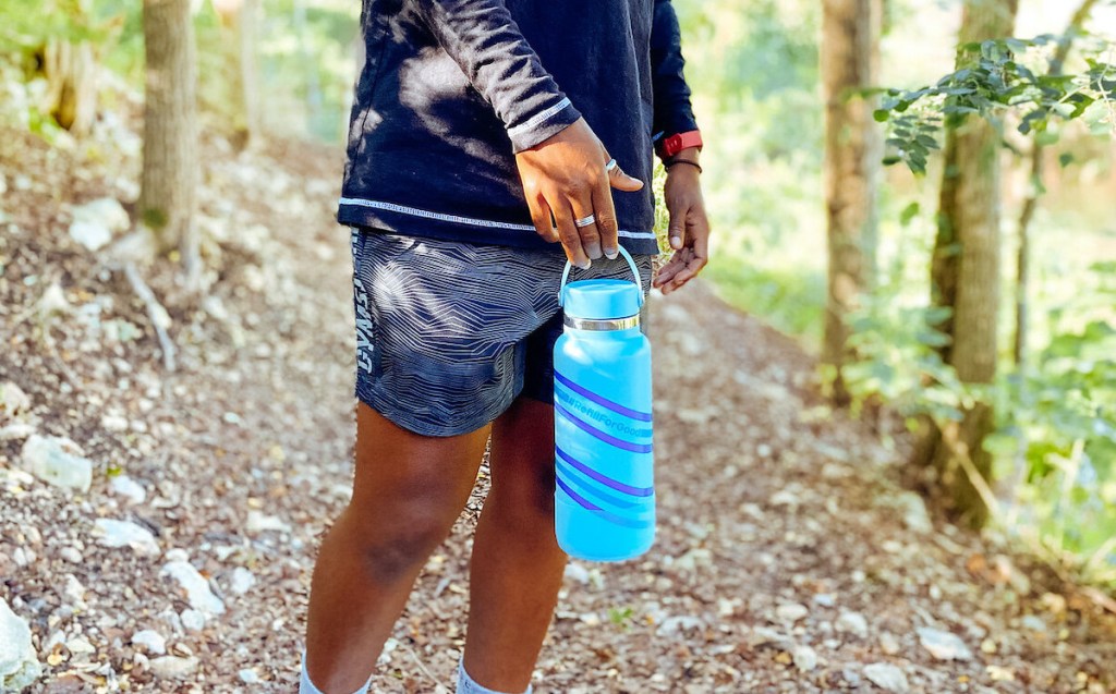 close up of person holding blue hydro flask handle in woods
