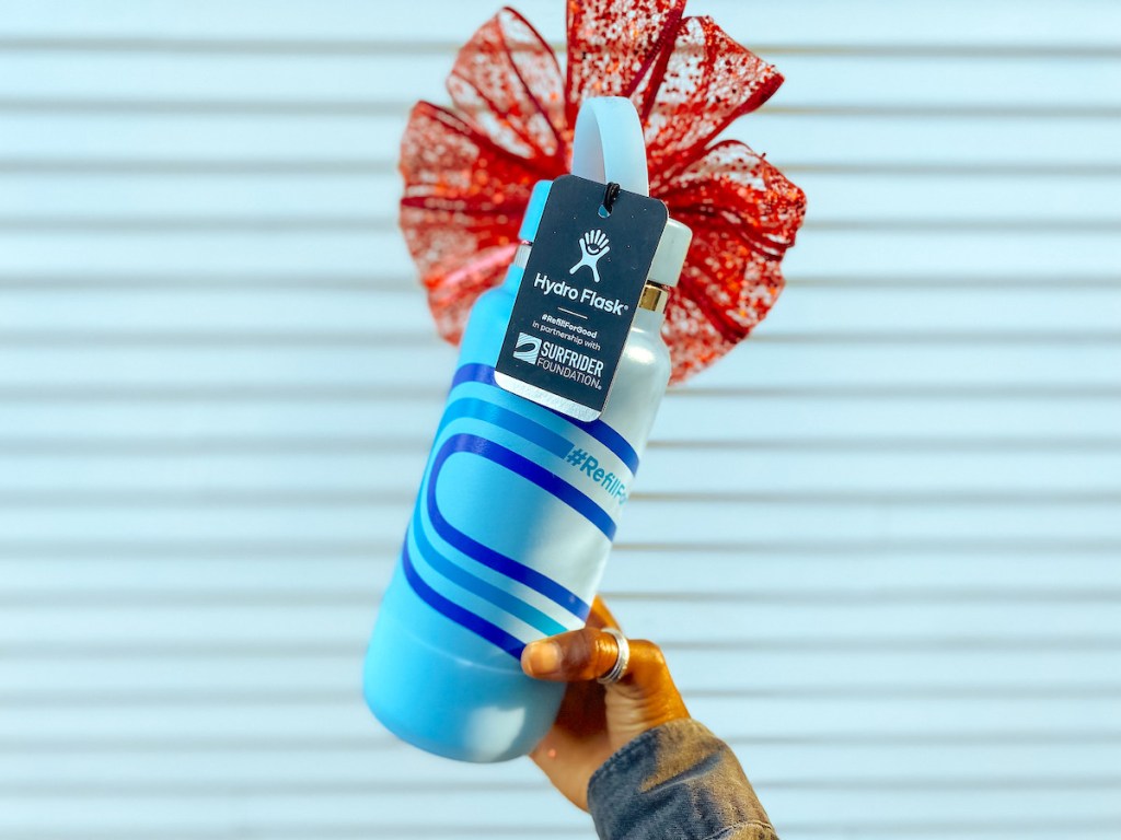 hand holding blue limited edition hydro flask bottle with red bow