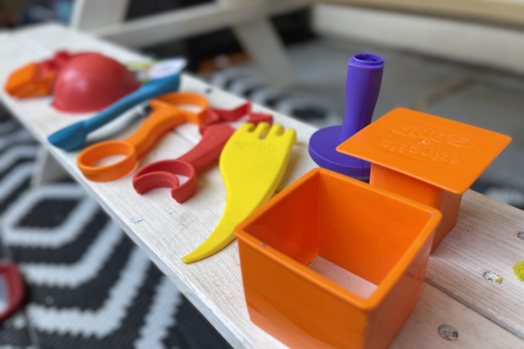 many kinetic sand tools lined up on a bench