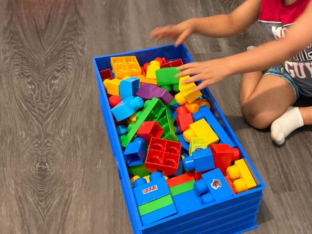 kid putting legos in lego box