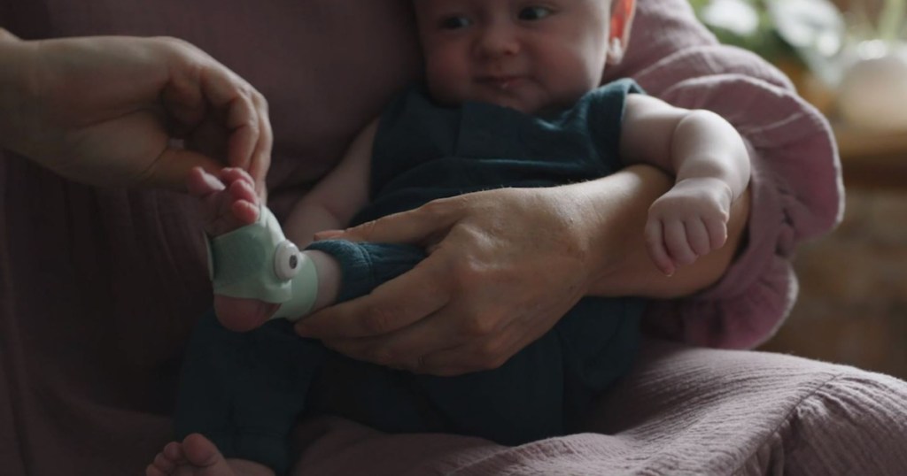 person holding baby and putting sock on him
