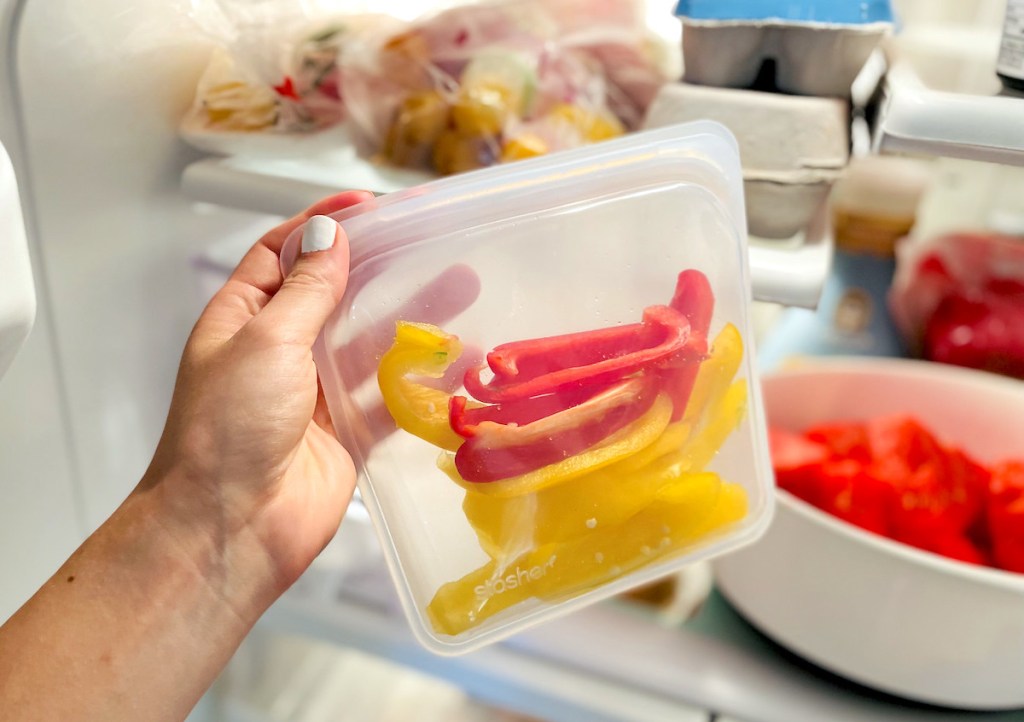 hand holding a clear stasher bag with red and yellow sliced pepper