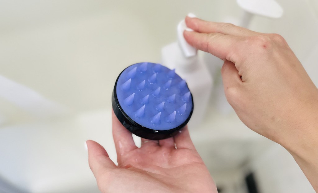 hand pumping shampoo on black and purple circle brush