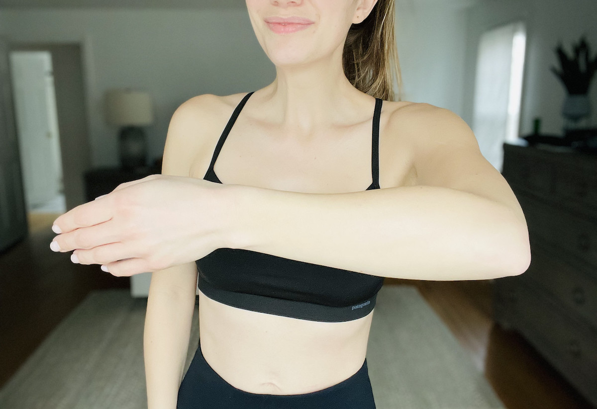 woman holding arm up wearing black workout clothes
