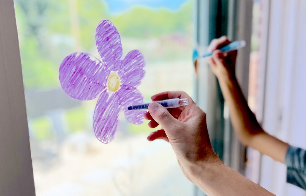 hand coloring with purple crayons on window 