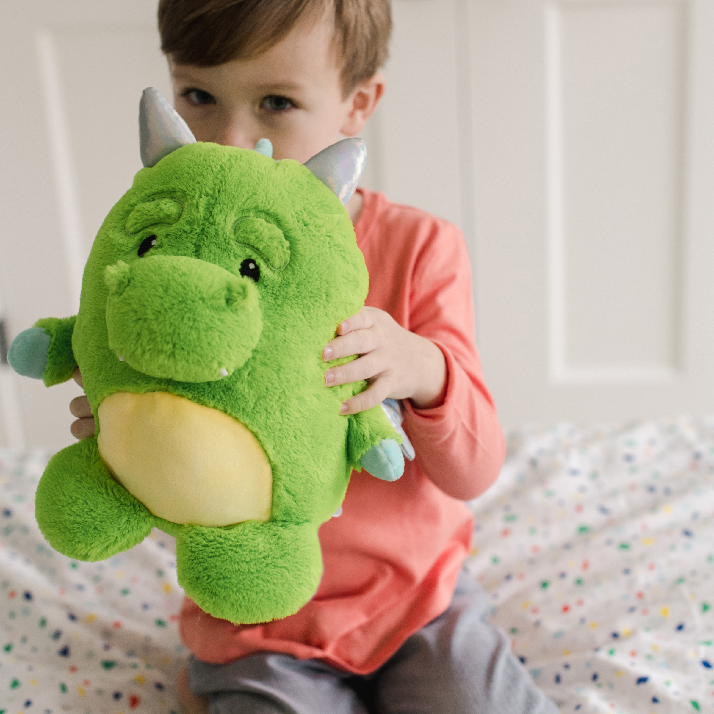 little boy holding a stuffed dragon plush