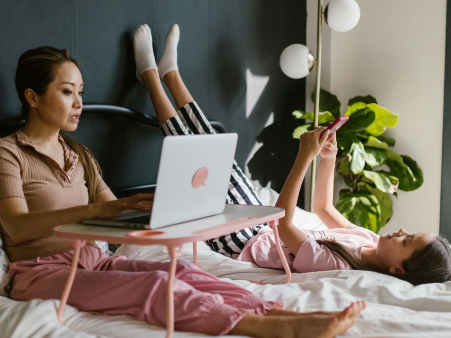 woman and girl in a bed using devices