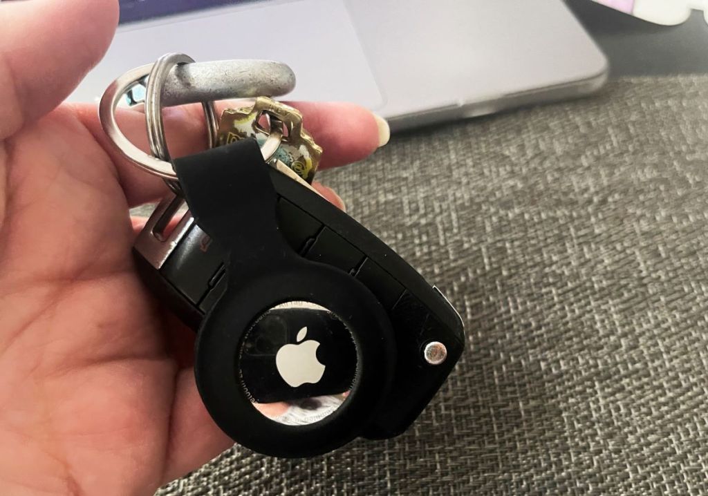 hand holding an Apple Airtag on a keychain