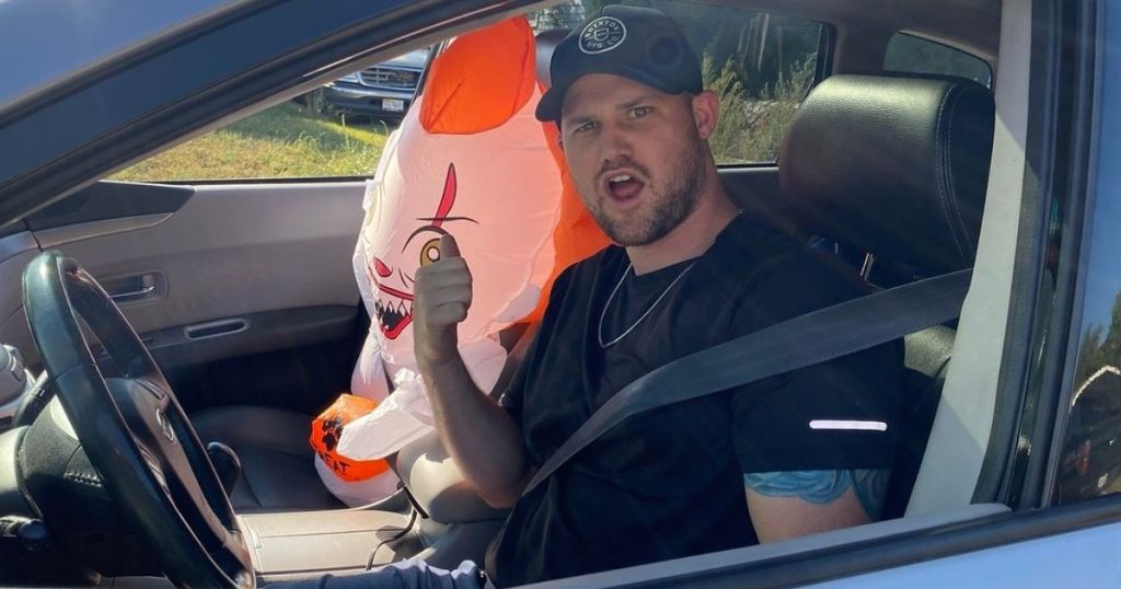 man in car with inflatable Pennywise clown