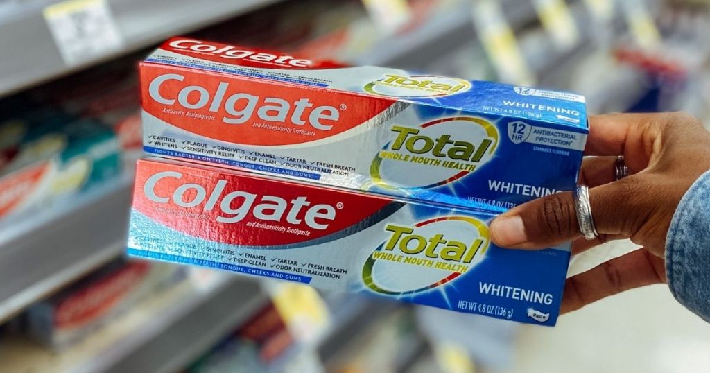 hand holding two boxes of Colgate Toothpaste boxes