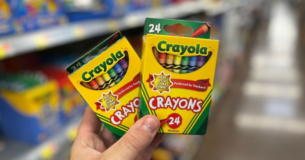 hand holding two boxes of Crayola Crayons