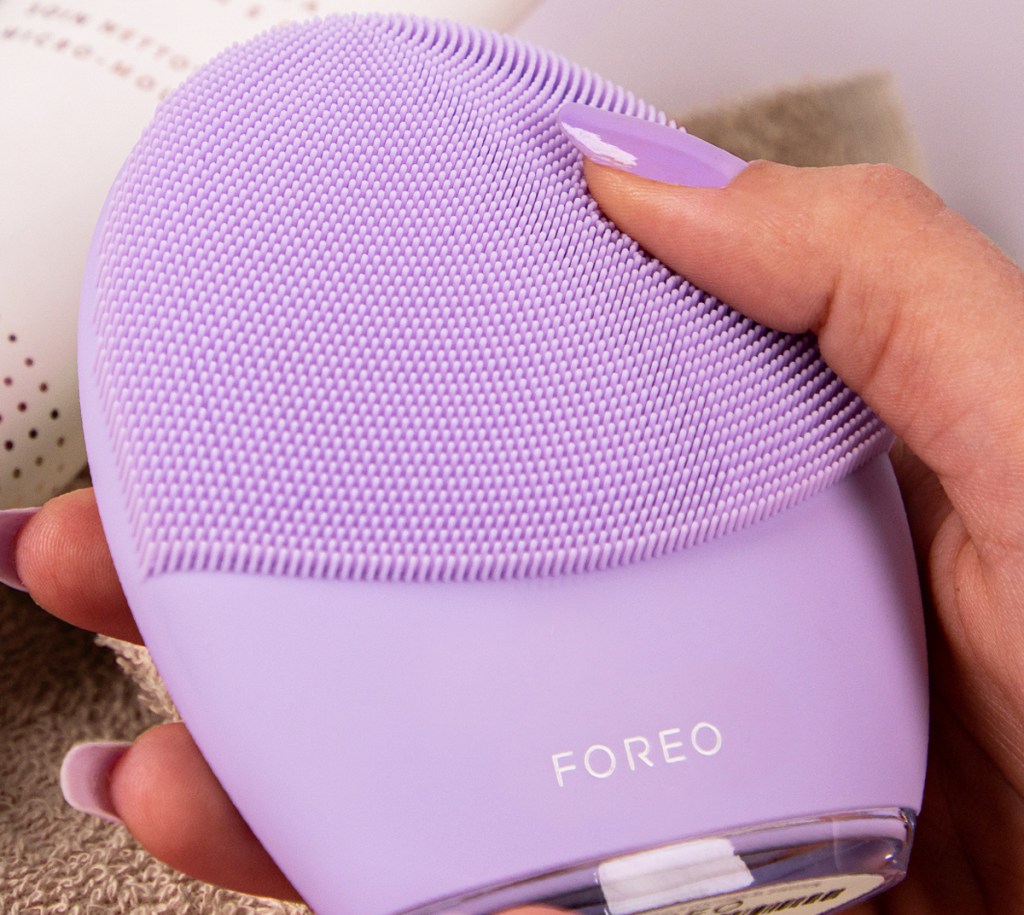 hand holding a purple foreo facial brush