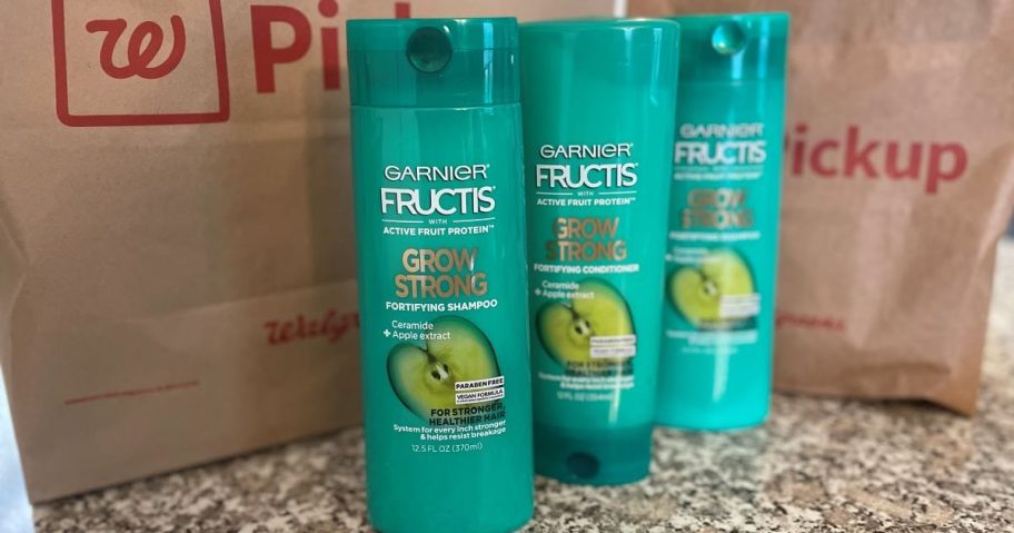 three bottles of Garnier Fructis by a Walgreens bag