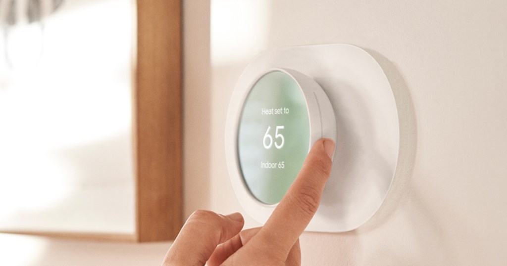 hand touching a google nest thermostat