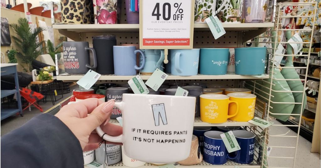 hand holding up a coffee mug in front of a display of mugs with a sig that says 40% off